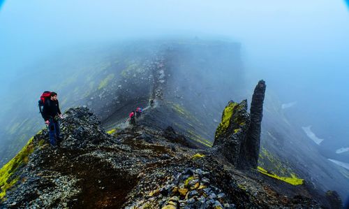 High angle view of people hiking on mountain during foggy weather