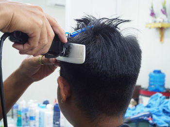 Cropped hands of barber cutting customer hair in salon