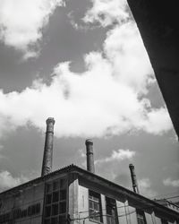 Low angle view of factory against cloudy sky