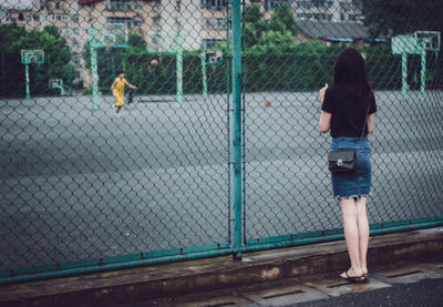 Man standing on chainlink fence