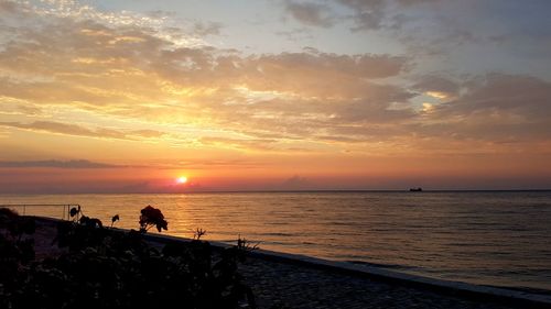 Silhouette people on beach against sky during sunset