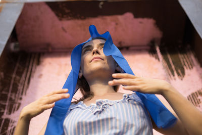 Low angle view of woman wearing headscarf against wall