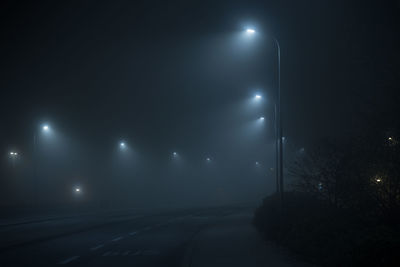 Illuminated road against sky at night