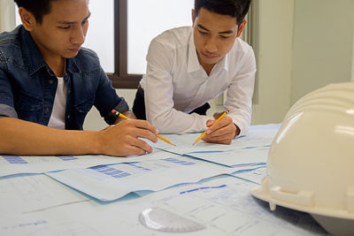 Architect working over blueprint at table in office