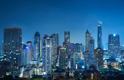 Illuminated buildings in city against sky at night