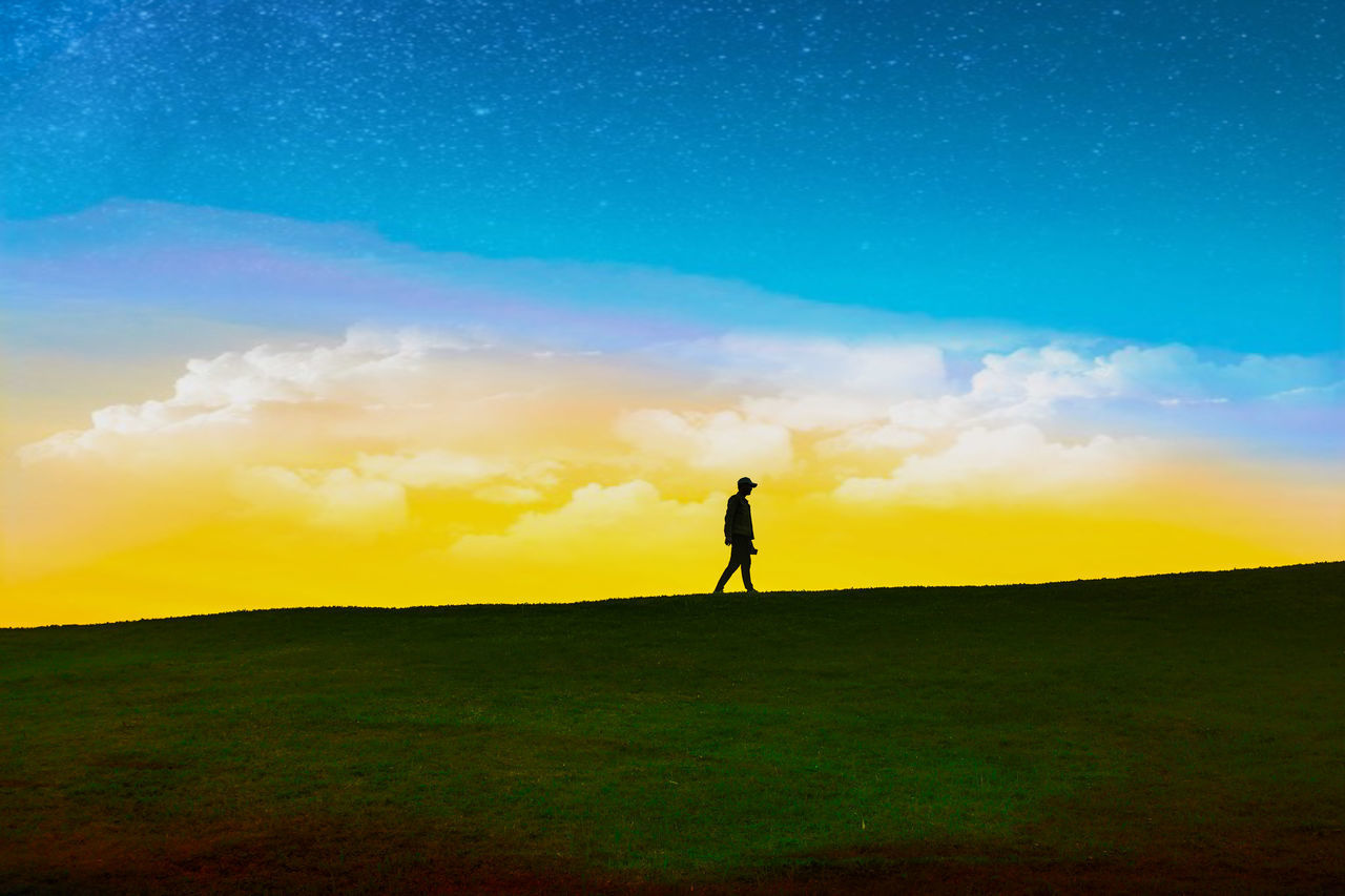 SILHOUETTE MAN STANDING ON FIELD AGAINST SKY