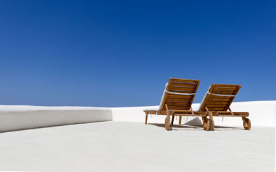 Two wooden deckchairs on white terrace