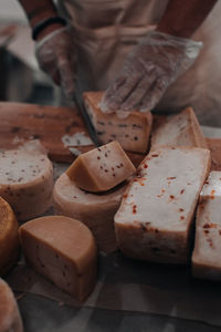 Man's hand with knife cutting a cheese on the wooden board on the table in the kitchen. healthy