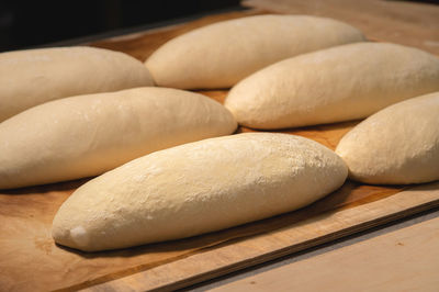 Several loaves of raw dough lie on a wooden board. craft bread before baking