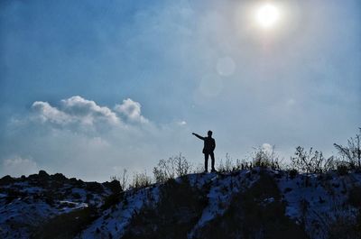 Silhouette of man standing on snow covered landscape against sky