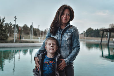 Portrait of smiling happy woman against lake