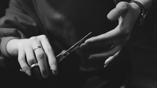 Midsection of woman cutting nail from scissor