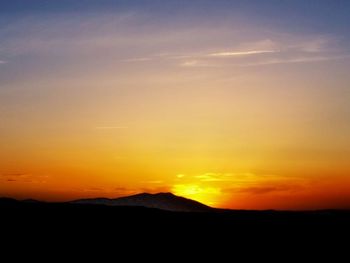 Scenic view of silhouette mountains against orange sky