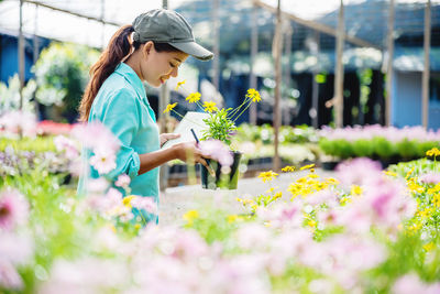 Side view of woman holding flowering plants