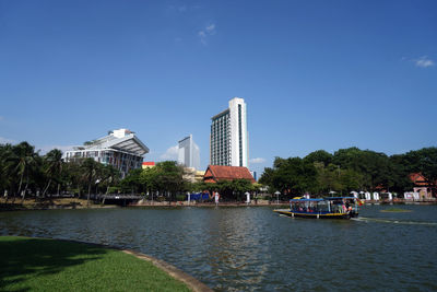 View of buildings by river against blue sky