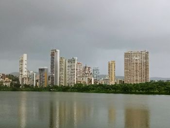 Buildings by river against sky in city