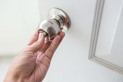 Close-up of hand holding white doorknob at home