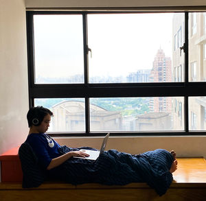 Side view of man using laptop while relaxing on table