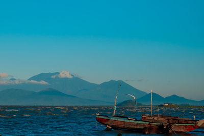 Boats moored in sea against mountains