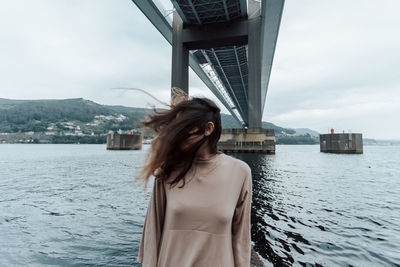 Portrait of young woman standing against river