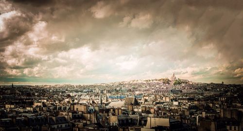 Aerial view of cityscape against storm clouds