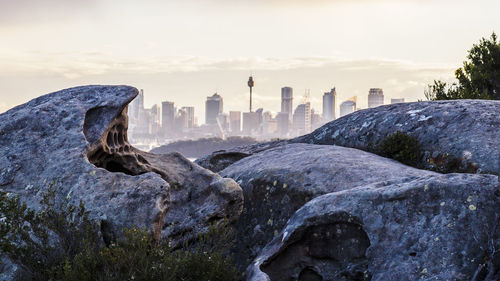 Rocks by sydney tower and city skyline against sky