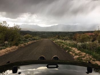 Road amidst field against sky