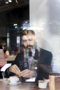 Portrait of young man using mobile phone at cafe