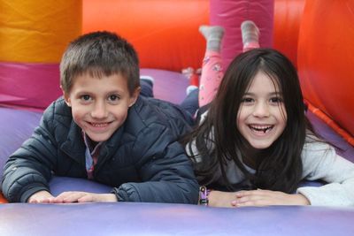 Portrait of happy siblings playing on mattress