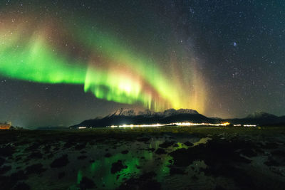 Northern lights over mountains at the rocky seashore
