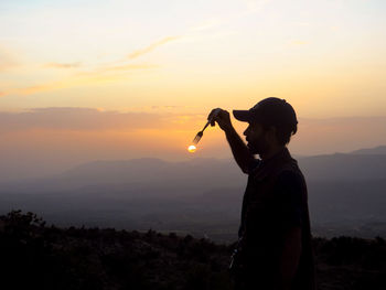 Silhouette man standing on mountain against sky during sunset