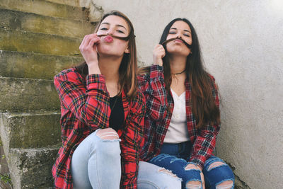 Portrait of friends puckering lips while sitting on steps