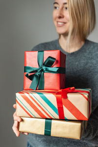 Unrecognizable woman holds a stack of beautifully wrapped christmas presents.