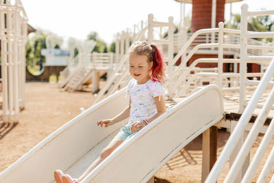 Cute little girl rides down a slide on the playground
