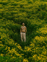 Portrait of woman standing amidst yellow flowering plants on field