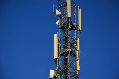 Low angle view of communications tower against clear blue sky