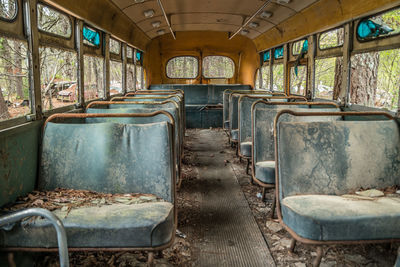 Inside view of a abandoned vintage school bus with seats and broken windows and a rotting interior 