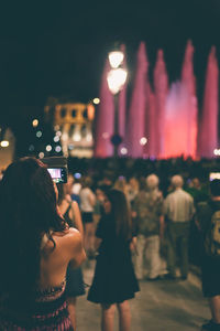 Rear view of woman using smart phone at night