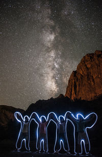 Digital composite image of illuminated lights against sky at night