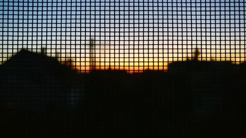 Close-up of silhouette of railings against sunset sky