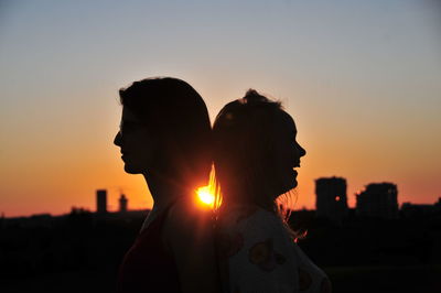 Portrait of young woman standing against sky during sunset