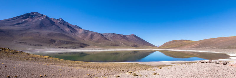 Scenic view of lake and mountains against clear blue sky