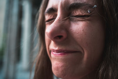 Close-up wide-angle portrait of young woman smiling eyes closed