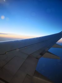 Airplane wing against sky during sunset