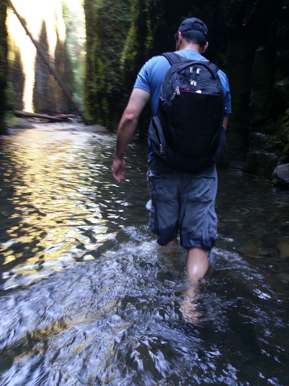 REAR VIEW OF MAN WALKING BY WATER