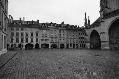 Paved path with buildings against sky