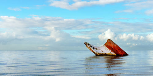 Abandoned boat in sea against sky