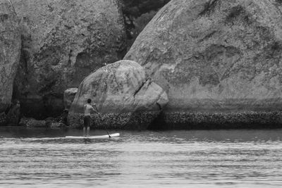 Man standing on rock by sea