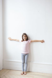 Portrait of smiling girl standing against wall at home