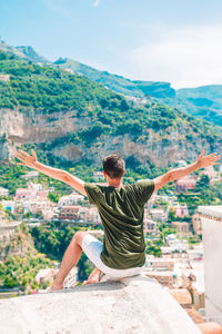 Man sitting by wall with mountain in background